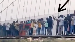 कुछ लड़के हिला रहे थे पुल, स्टाफ को बताया लेकिन वो टिकट बेचते रहे; घटनास्थल पर मौजूद शख्स का दावा अहमदाबाद के रहने वाले विजय गोस्वामी और उनके परिवार के लोग मोरबी में हुए पुल हादसे में बाल-बाल बच गए। गोस्वामी पूरे परिवार के साथ रविवार को हुए भीषण हादसे से कुछ घंटे पहले ही पुल पर गए थे, लेकिन युवकों की ओर से केबल पुल हिलाए जाने के कारण वह नीचे उतर आए। हालांकि, कुछ घंटों बाद उनका डर सही साबित हुआ और पर्यटकों के लिए आकर्षण का केंद्र मच्छु नदी पर बना केबल पुल शाम करीब 6:30 बजे टूट गया। हादसे में 132 लोगों की मौत हो गई है। गोस्वामी ने कहा कि जब वह और उनका परिवार पुल पर था तो कुछ युवक जानबूझ कर पुल को हिला रहे थे, उस कारण पुल पर लोगों का चलना भी दूभर हो रहा था। गोस्वामी को लगा कि इससे खतरा हो सकता है। वह और उनका परिवार पुल से नीचे उतर आए। उन्होंने बताया कि इसके बारे में उन्होंने पुल के कर्मचारियों को भी सूचना दी, लेकिन उन्होंने उसे नजरअंदाज कर दिया। ब्रिटिश काल में बना यह पुल मरम्मत के बाद चार दिन पहले ही लोगों के लिए खुला था। 'कुछ युवक जानबूझकर हिला रहे थे पुल' गोस्वामी ने कहा कि वह दीवाली की छुट्टियों में परिवार के साथ मोरबी आए थे। अहमदाबाद पहुंचने के बाद गोस्वामी ने बताया, 'पुल पर बहुत भीड़ थी। जब मैं और मेरा परिवार वहां पहुंचे तो कुछ युवक जानबूझकर पुल को हिला रहे थे। लोगों के लिए बिना सहारे के उसपर खड़ा होना मुश्किल था। चूंकि मुझे लगा कि यह खतरनाक साबित हो सकता है, मैं पुल पर कुछ दूर चढ़ने के बाद ही परिवार के साथ नीचे उतर आया।' उन्होंने कहा, 'वहां से जाने से पहले मैंने ड्यूटी पर मौजूद कर्मचारी को लोगों को पुल हिलाने से रोकने को भी कहा। लेकिन, उन्हें सिर्फ टिकट बेचने में दिलचस्पी थी और उन्होंने कहा कि भीड़ को नियंत्रित करने का कोई उपाय नहीं है। हमारे वहां से जाने के कुछ ही घंटे बाद हमारा डर सच हो गया और पुल टूट गया।' सोशल मीडिया पर वीडियो वायरल सोशल मीडिया पर वायरल हुए एक वीडियो में कुछ युवकों को पुल के केबल को लात मारते और दूसरे लोगों को डराने के लिए पुल को हिलाते देखा जा सकता है। मौके पर मौजूद कई बच्चों ने बताया कि पुल गिरने के बाद उनके परिवार के सदस्य या माता-पिता अभी तक लापता हैं। 10 साल के एक बच्चे ने बताया, 'बहुत भीड़ थी, तभी पुल अचानक टूट गया। मैं बच गया क्योंकि मैंने एक रस्सी पकड़ ली थी और फिर धीरे-धीरे उससे ऊपर आ गया। लेकिन मेरे मम्मी-पापा अभी भी लापता हैं।' हादसे में बालबाल बचे मेहुल रावल ने बताया कि पुल जब टूटा उस वक्त उसपर करीब 300 लोग खड़े होंगे। मोरबी के अस्पताल में भर्ती रावल ने बताया, 'जब हम पुल पर थे, तभी वह अचानक बीच से दबने लगा। सभी लोग नीचे गिर गए। कई लोग मर गए जबकि कई लोग घायल हो गए। पुल पर बहुत ज्यादा लोग थे, इसलिए वह गिर गया।' 'पुल पर रहे होंगे करीब 300 लोग' एक स्थानीय निवासी ने कहा, 'कुछ ही दिन पहले लोगों के लिए फिर से खोले गए पुल पर करीब 300 लोग रहे होंगे। ज्यादातर हताहत बच्चे हैं, क्योंकि वे सभी दीवाली की छुट्टियों में आए थे। स्थानीय लोग तत्काल मौके पर पहुंचे और जितना संभव हो सका लोगों को सुरक्षित बाहर निकाला। हादसे के बाद मोरबी के सभी हिस्सों से बड़ी संख्या में लोग राहत और बचाव के लिए मौके पर पहुंच गए।' कुछ लड़के हिला रहे थे पुल, स्टाफ को बताया लेकिन वो टिकट बेचते रहे; घटनास्थल पर मौजूद शख्स का दावा अहमदाबाद के रहने वाले विजय गोस्वामी और उनके परिवार के लोग मोरबी में हुए पुल हादसे में बाल-बाल बच गए। गोस्वामी पूरे परिवार के साथ रविवार को हुए भीषण हादसे से कुछ घंटे पहले ही पुल पर गए थे, लेकिन युवकों की ओर से केबल पुल हिलाए जाने के कारण वह नीचे उतर आए। हालांकि, कुछ घंटों बाद उनका डर सही साबित हुआ और पर्यटकों के लिए आकर्षण का केंद्र मच्छु नदी पर बना केबल पुल शाम करीब 6:30 बजे टूट गया। हादसे में 132 लोगों की मौत हो गई है। गोस्वामी ने कहा कि जब वह और उनका परिवार पुल पर था तो कुछ युवक जानबूझ कर पुल को हिला रहे थे, उस कारण पुल पर लोगों का चलना भी दूभर हो रहा था। गोस्वामी को लगा कि इससे खतरा हो सकता है। वह और उनका परिवार पुल से नीचे उतर आए। उन्होंने बताया कि इसके बारे में उन्होंने पुल के कर्मचारियों को भी सूचना दी, लेकिन उन्होंने उसे नजरअंदाज कर दिया। ब्रिटिश काल में बना यह पुल मरम्मत के बाद चार दिन पहले ही लोगों के लिए खुला था। 'कुछ युवक जानबूझकर हिला रहे थे पुल' गोस्वामी ने कहा कि वह दीवाली की छुट्टियों में परिवार के साथ मोरबी आए थे। अहमदाबाद पहुंचने के बाद गोस्वामी ने बताया, 'पुल पर बहुत भीड़ थी। जब मैं और मेरा परिवार वहां पहुंचे तो कुछ युवक जानबूझकर पुल को हिला रहे थे। लोगों के लिए बिना सहारे के उसपर खड़ा होना मुश्किल था। चूंकि मुझे लगा कि यह खतरनाक साबित हो सकता है, मैं पुल पर कुछ दूर चढ़ने के बाद ही परिवार के साथ नीचे उतर आया।' उन्होंने कहा, 'वहां से जाने से पहले मैंने ड्यूटी पर मौजूद कर्मचारी को लोगों को पुल हिलाने से रोकने को भी कहा। लेकिन, उन्हें सिर्फ टिकट बेचने में दिलचस्पी थी और उन्होंने कहा कि भीड़ को नियंत्रित करने का कोई उपाय नहीं है। हमारे वहां से जाने के कुछ ही घंटे बाद हमारा डर सच हो गया और पुल टूट गया।' सोशल मीडिया पर वीडियो वायरल सोशल मीडिया पर वायरल हुए एक वीडियो में कुछ युवकों को पुल के केबल को लात मारते और दूसरे लोगों को डराने के लिए पुल को हिलाते देखा जा सकता है। मौके पर मौजूद कई बच्चों ने बताया कि पुल गिरने के बाद उनके परिवार के सदस्य या माता-पिता अभी तक लापता हैं। 10 साल के एक बच्चे ने बताया, 'बहुत भीड़ थी, तभी पुल अचानक टूट गया। मैं बच गया क्योंकि मैंने एक रस्सी पकड़ ली थी और फिर धीरे-धीरे उससे ऊपर आ गया। लेकिन मेरे मम्मी-पापा अभी भी लापता हैं।' हादसे में बालबाल बचे मेहुल रावल ने बताया कि पुल जब टूटा उस वक्त उसपर करीब 300 लोग खड़े होंगे। मोरबी के अस्पताल में भर्ती रावल ने बताया, 'जब हम पुल पर थे, तभी वह अचानक बीच से दबने लगा। सभी लोग नीचे गिर गए। कई लोग मर गए जबकि कई लोग घायल हो गए। पुल पर बहुत ज्यादा लोग थे, इसलिए वह गिर गया।' 'पुल पर रहे होंगे करीब 300 लोग' एक स्थानीय निवासी ने कहा, 'कुछ ही दिन पहले लोगों के लिए फिर से खोले गए पुल पर करीब 300 लोग रहे होंगे। ज्यादातर हताहत बच्चे हैं, क्योंकि वे सभी दीवाली की छुट्टियों में आए थे। स्थानीय लोग तत्काल मौके पर पहुंचे और जितना संभव हो सका लोगों को सुरक्षित बाहर निकाला। हादसे के बाद मोरबी के सभी हिस्सों से बड़ी संख्या में लोग राहत और बचाव के लिए मौके पर पहुंच गए।'